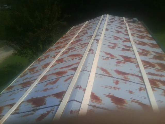 Rusted metal roof panels with new wood purlins before replacement — Storm Damage Roof Repair in Highland by Roofing Brothers