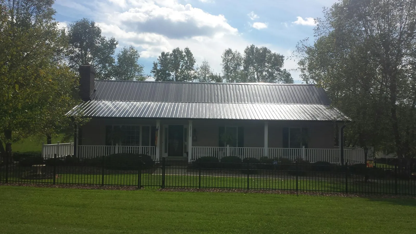 Gray metal roof on a brick ranch with a full width front porch — Gutter Guard Installation work by our crew in Highland