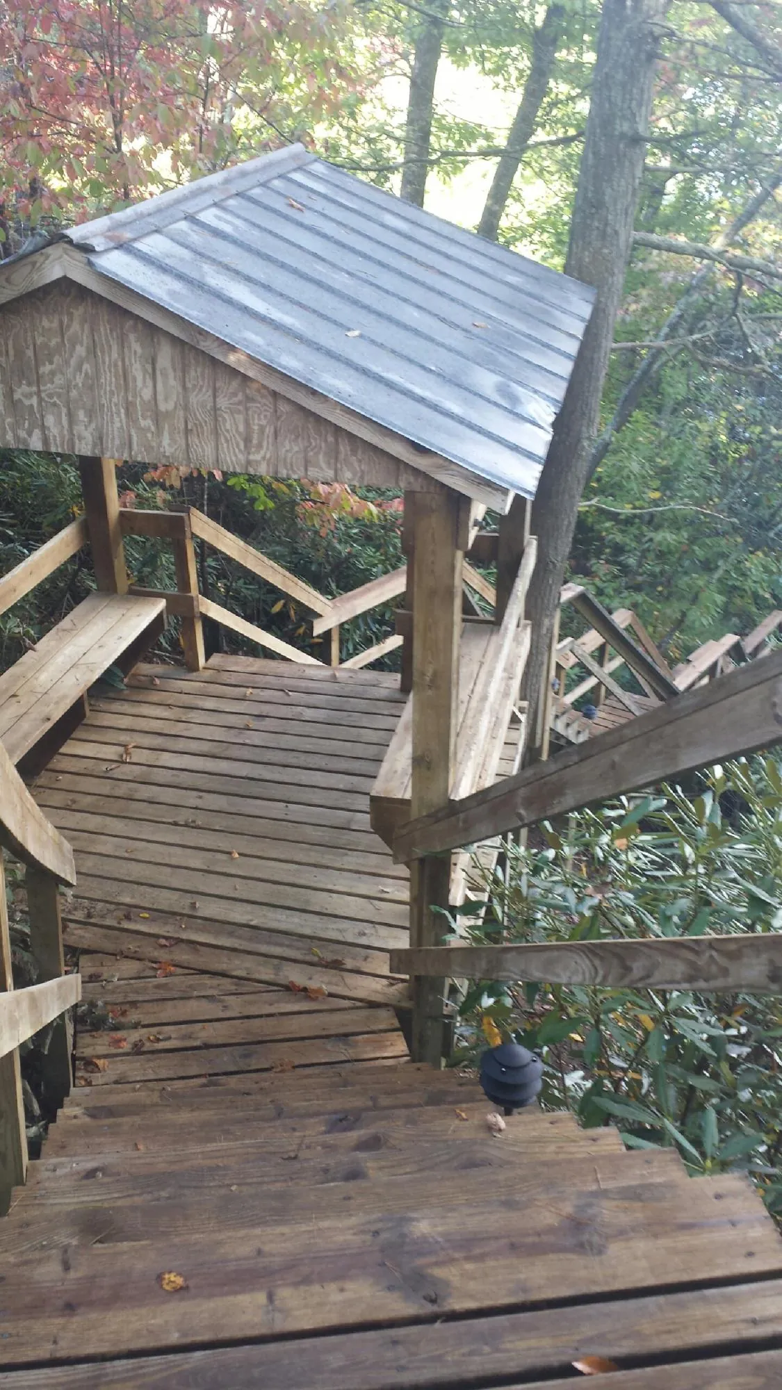 Metal roofed shelter over wooden steps on a wooded walkway — Skylight Repair & Installation work by our crew in Highland